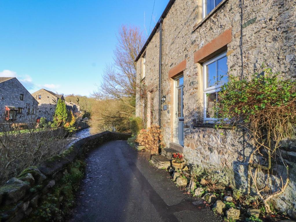 a stone building with a road next to a river at Waterfall Cottage in Carnforth