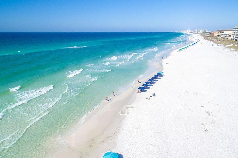 einen Strand mit blauen Sonnenschirmen und Menschen darauf in der Unterkunft Marvelous 9th Floor Condo Gulf, Pool &amp; Sunset View in Destin
