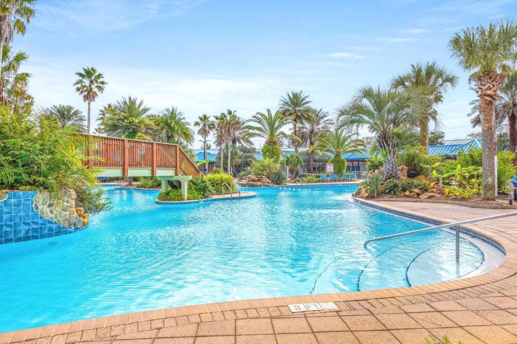 ein großer Swimmingpool mit Palmen in einem Resort in der Unterkunft Marvelous 9th Floor Condo Gulf, Pool &amp; Sunset View in Destin
