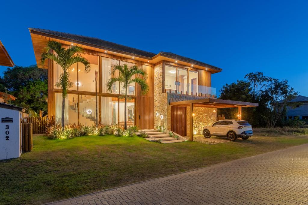 a house with a car parked in front of it at Casa Ofir - Alto Padrão - Serviços Inclusos in Praia do Forte