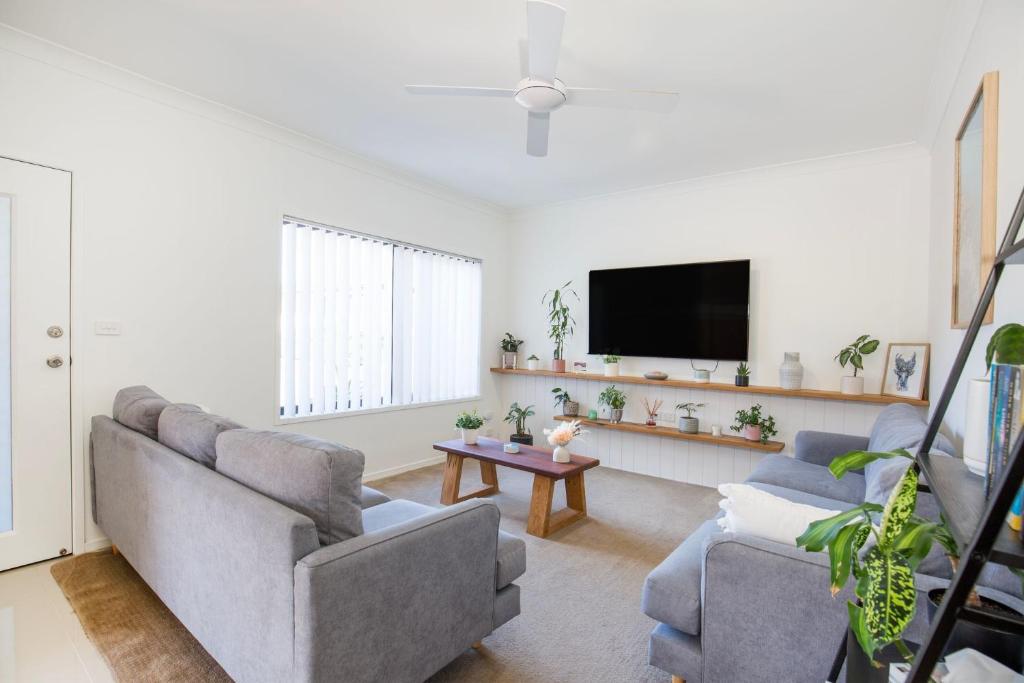 sala de estar con 2 sofás y TV de pantalla plana en The Palms Villa - Pet Friendly - 4 Mins to Beach, en Culburra Beach