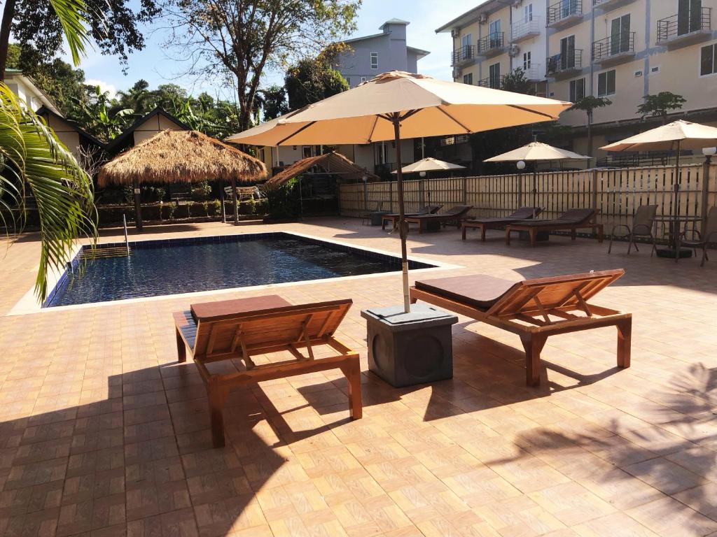 a pool with two chairs and a table and an umbrella at The White Elephant Resort in Ko Chang