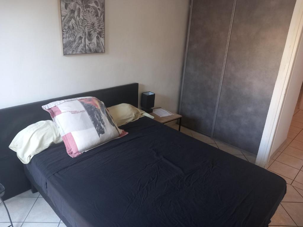 a bedroom with a black bed with two pillows on it at Chambre A2 dans un appartement en colocation in Marseille