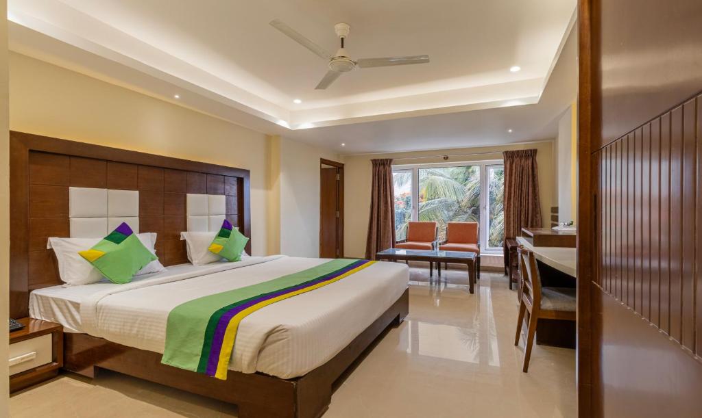 a bedroom with a large bed with a desk and a desk at Treebo Trend Suvarna Comforts in Hassan