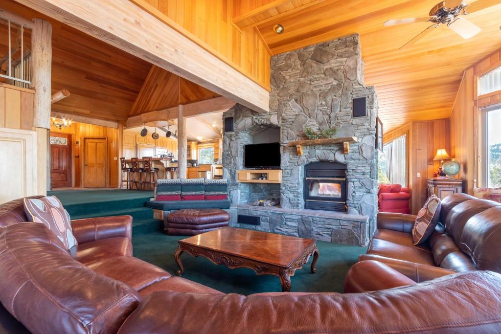 sala de estar con muebles de cuero y chimenea de piedra. en Timberline Lodge by AvantStay Secluded Hill Top Home w Incredible Views, en Big Bear Lake