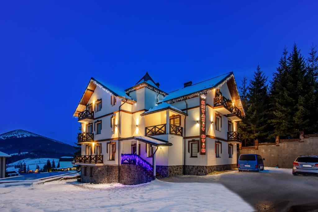 un gran edificio en la nieve por la noche en Князів Двір en Bukovel