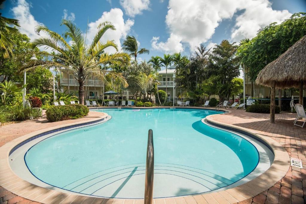 a swimming pool at a resort with a building in the background at Coral Villa by AvantStay Close 2 DT Key West Shared Pool Month Long Stays Only in Stock Island