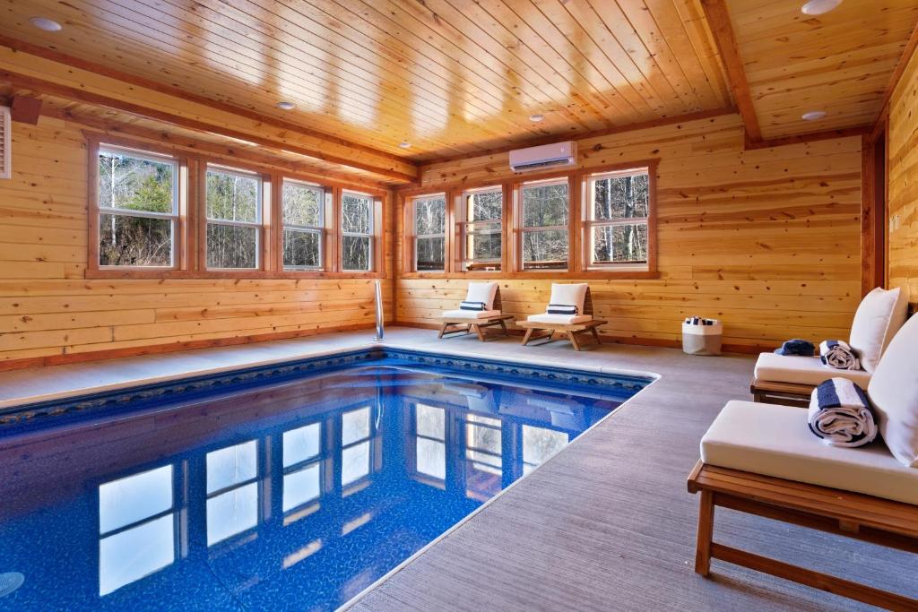 a swimming pool in a log cabin with windows at Haywood by AvantStay Mountain Living Dream w Movie Theatre Indoor Pool Hot Tub and Views in Sevierville