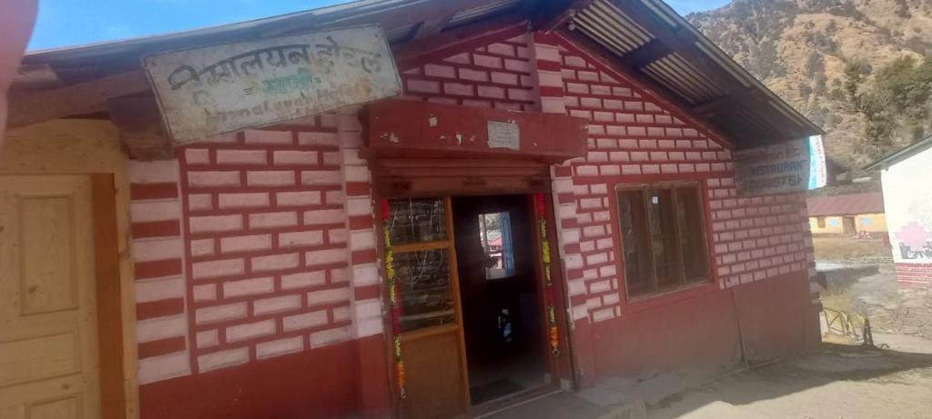 een klein rood bakstenen gebouw met een deur bij Himalayan Home stay in Bāgeshwar