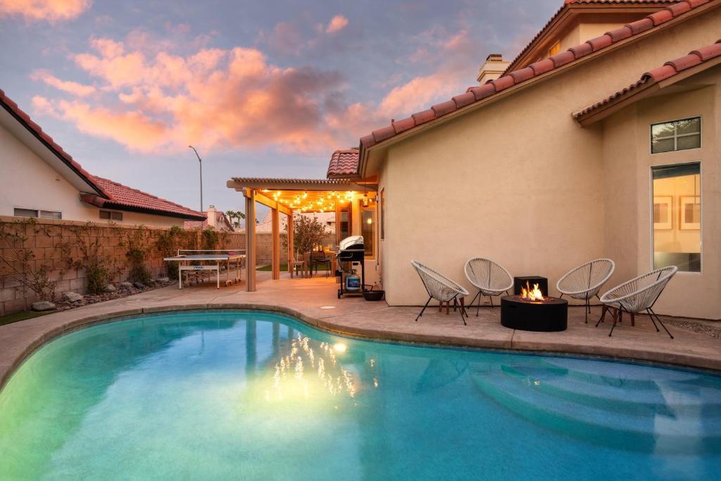 a swimming pool with chairs and a fire place next to a house at 5mins to Coachella Grounds Petit Sahara by AvantStay in La Quinta