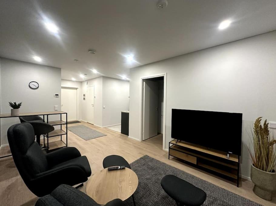 een woonkamer met zwarte stoelen en een televisie bij Kotimaailma Apartments#5 - Boheemi kaksio keskustassa in Seinäjoki