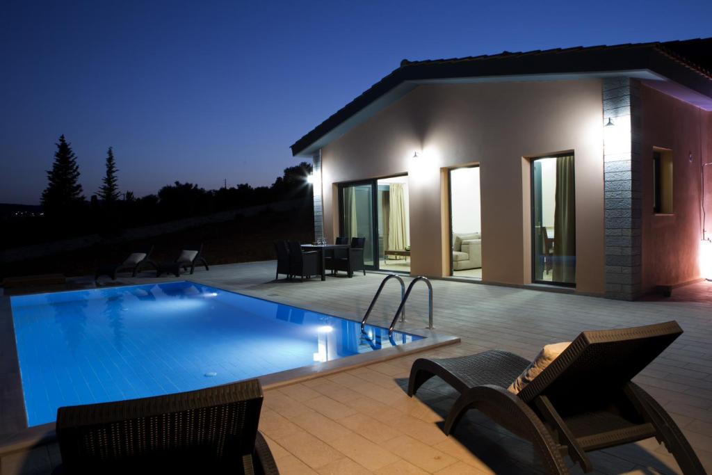 a swimming pool in front of a house at night at Nema Villas in Meganisi