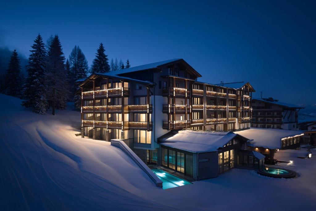 um grande edifício na neve à noite em Hotel Wulfenia 4S - Adults Only em Sonnenalpe Nassfeld