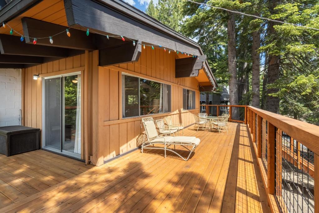 een houten terras met stoelen en een huis bij Fawn by AvantStay Secluded Cabin w Large Deck Surrounded by Forest in Tahoma Meadows