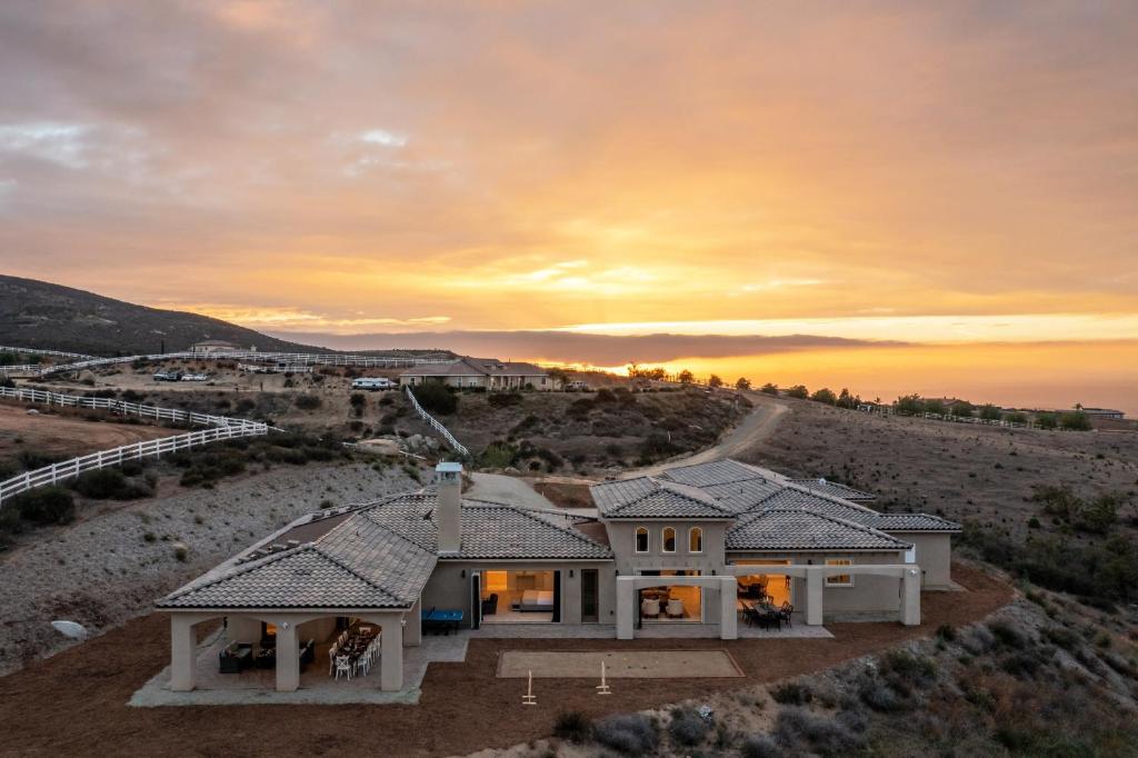 a house in the desert with a sunset in the background at Malbec by AvantStay Incredible Estate w Panoramic Views Bocce Ball Court in Sage