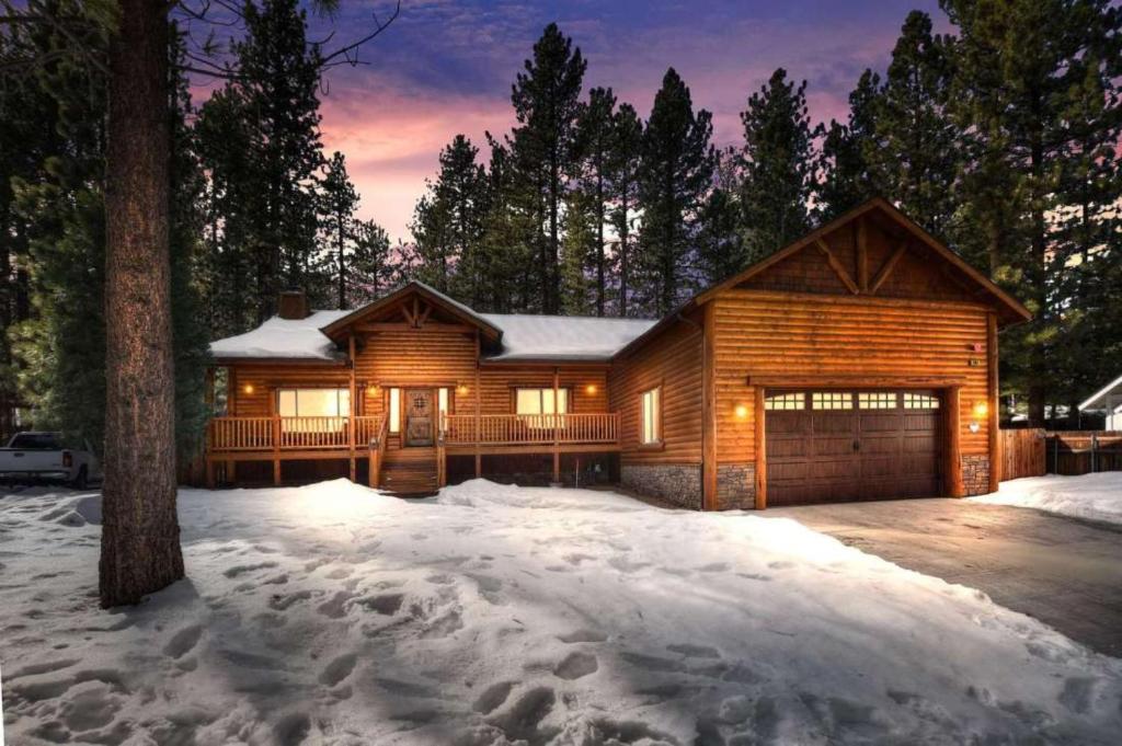 ein Holzhaus mit einer Garage im Schnee in der Unterkunft Paradise Pines by AvantStay Beautiful Big Bear Home Only 1 Mile To Snow Summit in Big Bear Lake