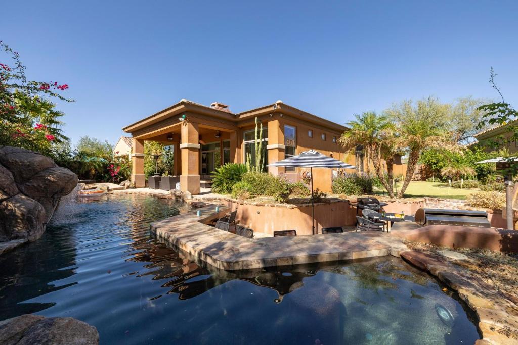 a house with a pond in front of it at Sandflower by AvantStay Oasis w Pool Golf in Phoenix