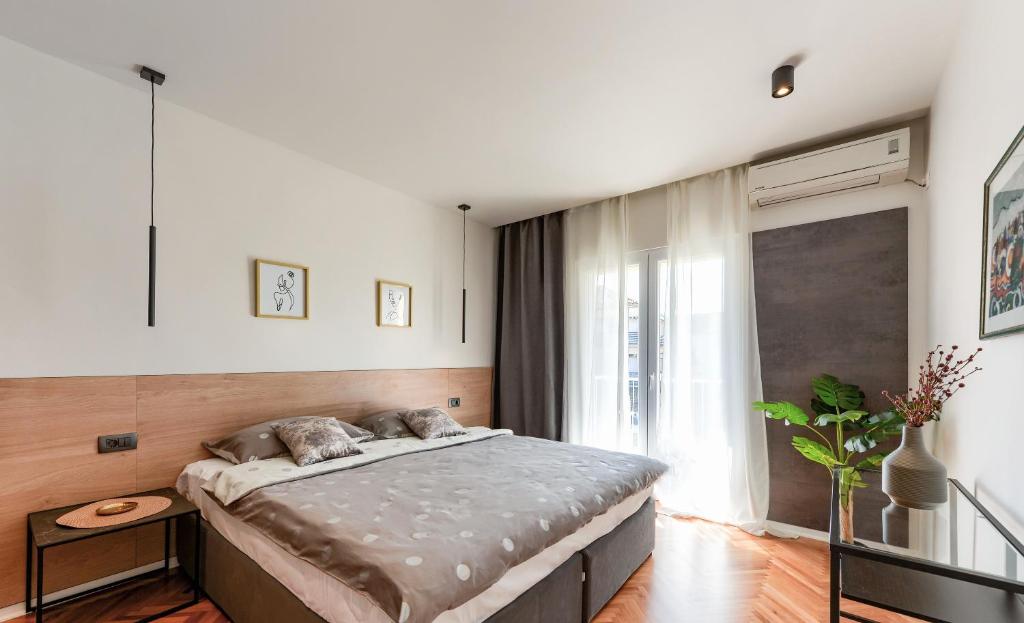 Bett in einem Zimmer mit einem großen Fenster in der Unterkunft Apartments Čolak in Zadar