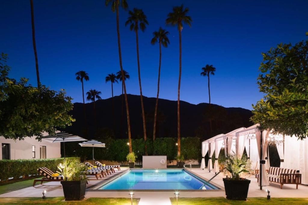 une piscine bordée de palmiers et un bâtiment dans l'établissement Hotel El Cid by AvantStay 16 OCC Full Hotel Buyout in Palm Springs w Pool, à Palm Springs