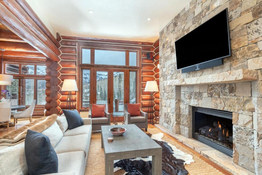 a living room with a stone fireplace and a tv at Villas At Tristant 137 by AvantStay Ski In Ski Out Home w Panoramic Views Hot Tub in Telluride