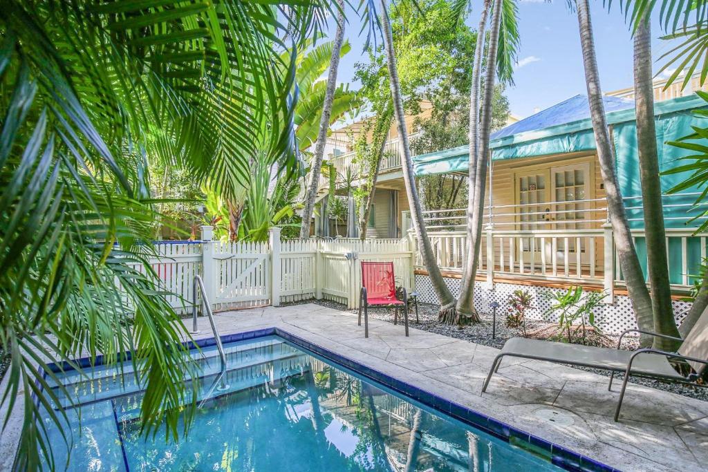 a house with a swimming pool and palm trees at Paradise Place by AvantStay Key West Old Town Condo w Shared Pool in Key West