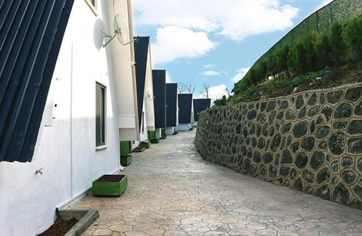 a stone walkway next to a building and a wall at Lara Bungalow Suit in Perşembe