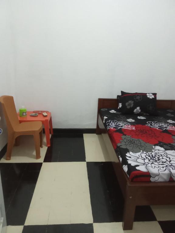 a bedroom with a bed and a chair and a table at K ADVENTURE HOMESTAY in Ketapang