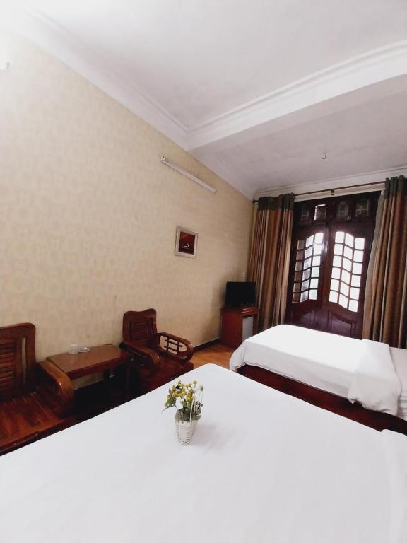 a bedroom with two beds and a table with flowers at Holiday Home in Hanoi