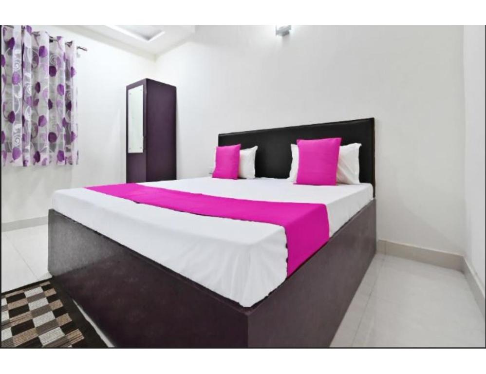 Schlafzimmer mit einem großen Bett mit rosa und weißer Bettwäsche in der Unterkunft Hotel Raj Inn, Agra in Agra
