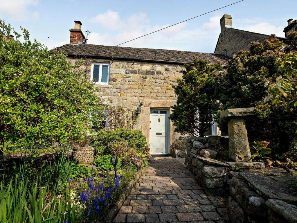 a stone house with a white door and a garden at 3 Bed in Baslow PK917 in Baslow