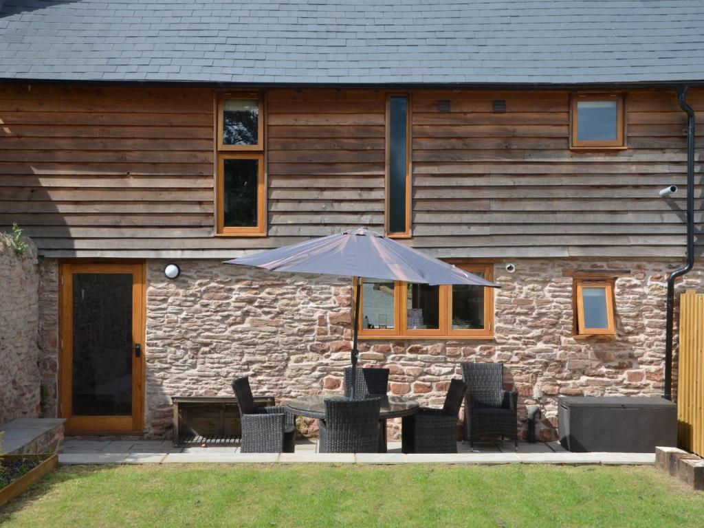 a table with an umbrella in front of a stone house at 3 Bed in Leominster 50507 in Pencombe