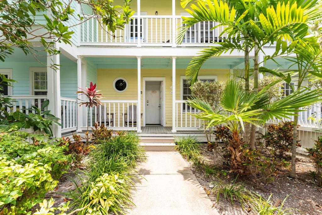 a house with a white door and palm trees at Conch Adventure by AvantStay Great Location w Patio Outdoor Dining and Shared Pool Week Long Stays in Key West