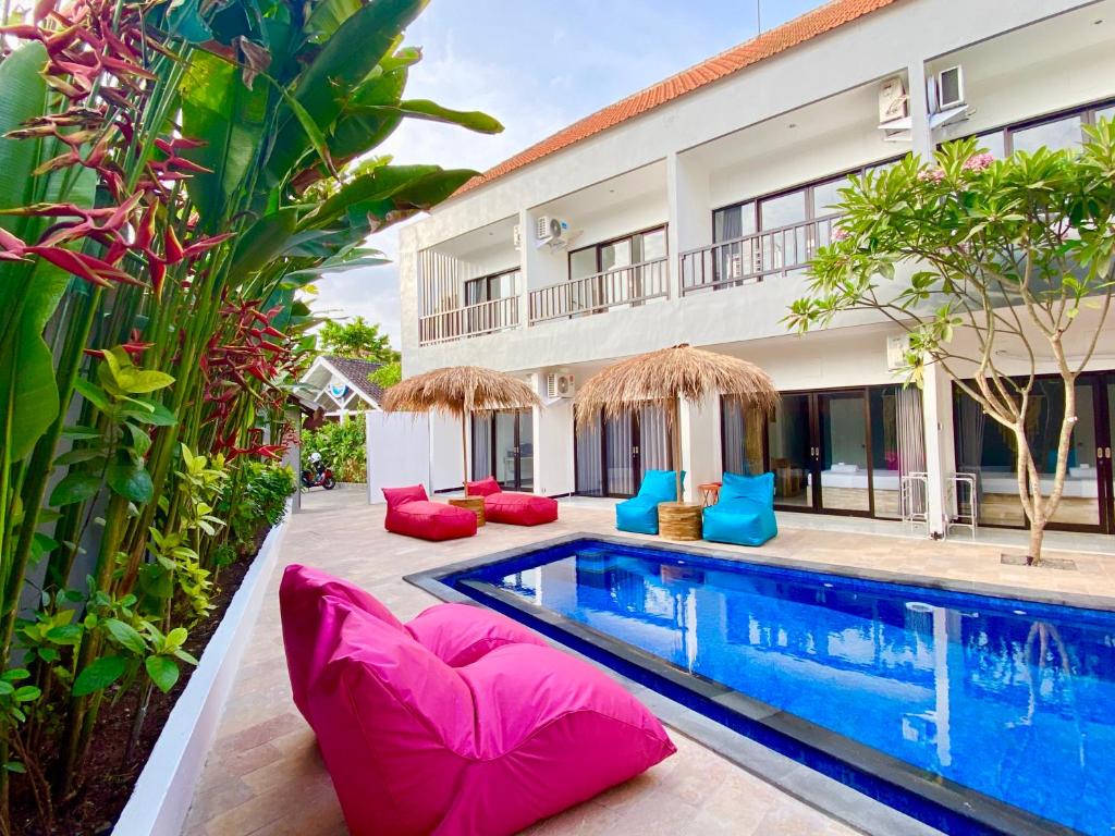 uma piscina em frente a uma casa com almofadas cor-de-rosa e azuis em Hotel Summer Of Surf em Ungasan