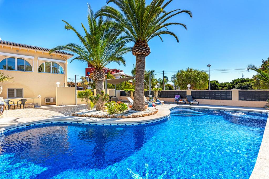 - une piscine bordée de palmiers en face d'une maison dans l'établissement Villa Campanilla - Plusholidays, à Calp