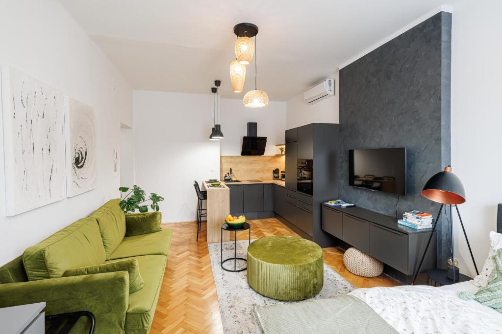 a living room with a green couch and a kitchen at New Green Studio Apartment near Tvrđa in Osijek