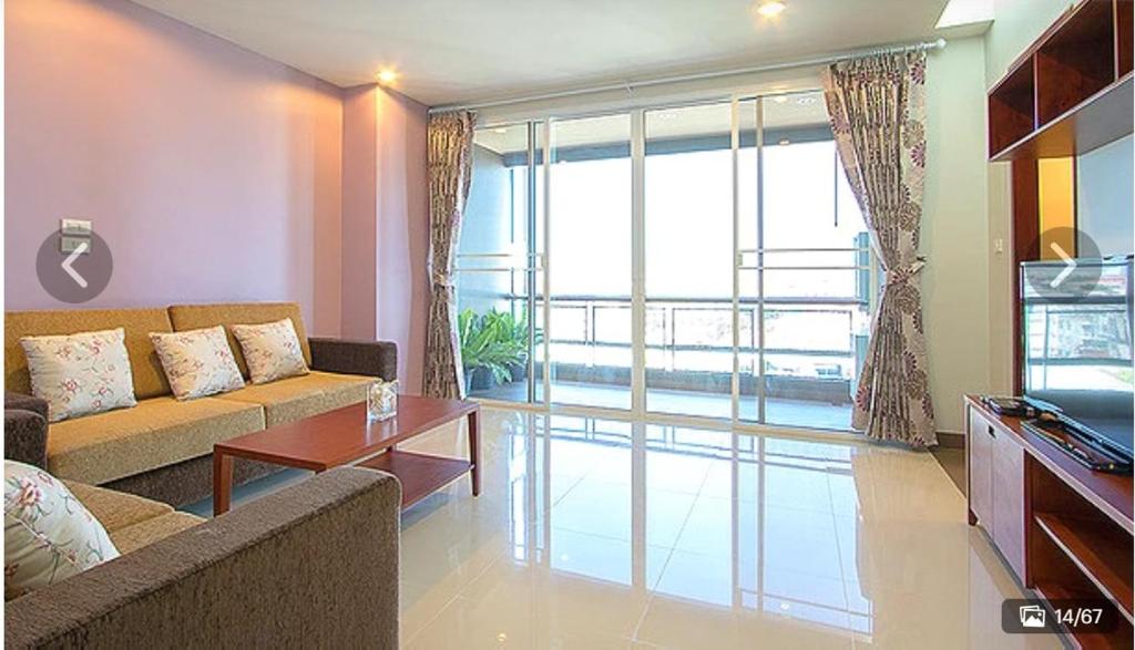 ein Wohnzimmer mit einem Sofa und einem großen Fenster in der Unterkunft Lasalle Park Serviced Apartment at Lasalle 75 in Bangna