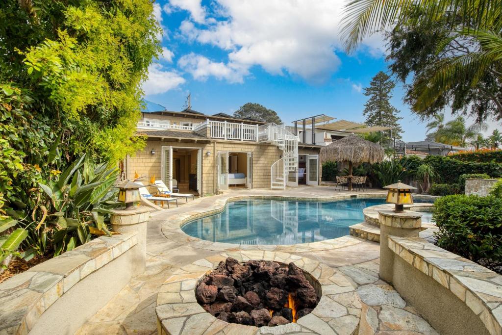 a swimming pool with a fire pit in front of a house at Wavebreak by AvantStay Close to BeachesSurfing in Solana Beach