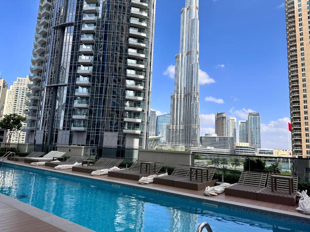 a swimming pool with lounge chairs and a city skyline at Burj Khalifa view - Modern 1BDR apartment in Dubai