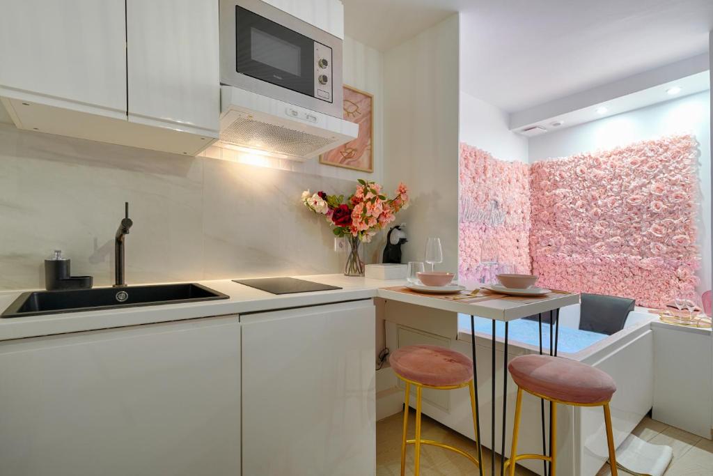 eine Küche mit weißen Schränken, einer Spüle und Stühlen in der Unterkunft La Vie en Rose / Jacuzzi in Montgeron