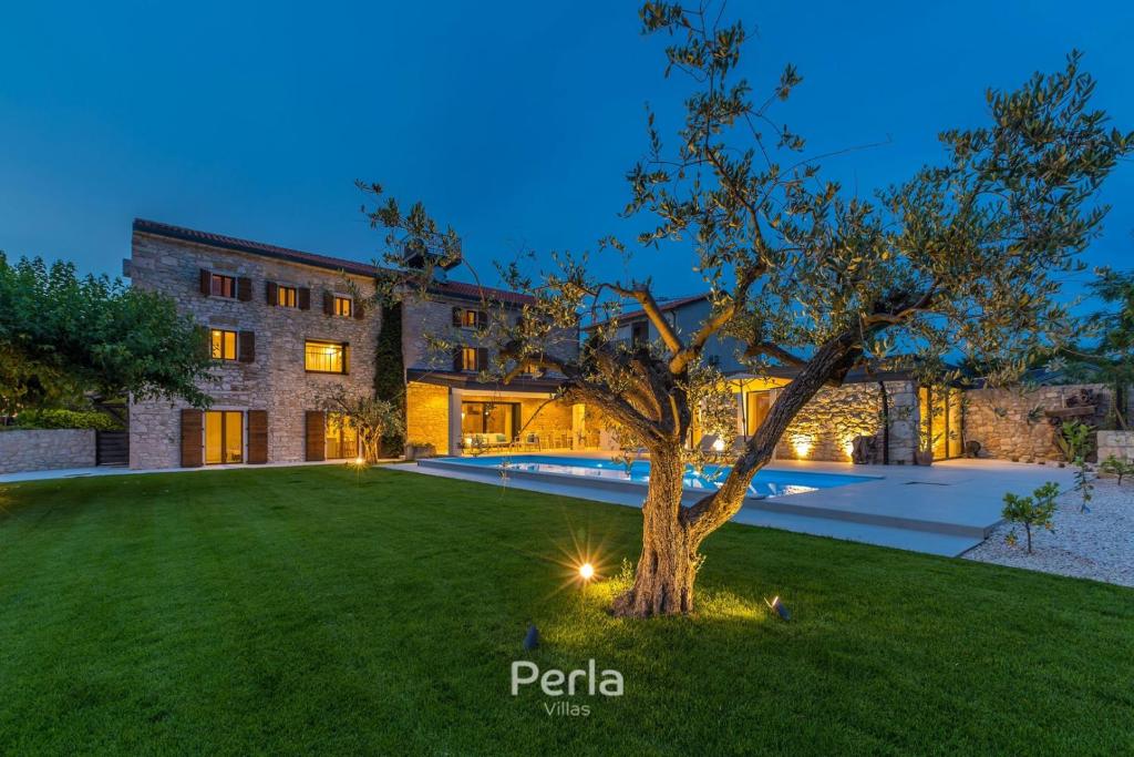 ein Haus mit einem Baum im Hof in der Unterkunft Charming stone Villa CX with large 50m2 heated pool in Brtonigla
