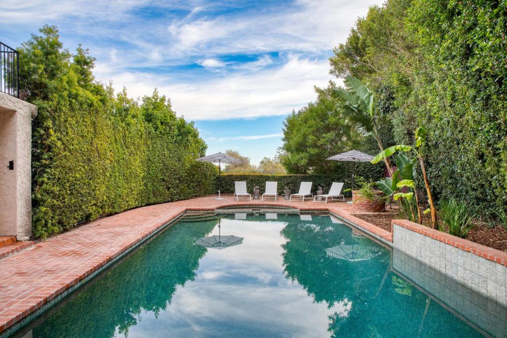 a swimming pool in a yard with chairs and trees at Dume Point by AvantStay Tennis Pool in Malibu in Malibu