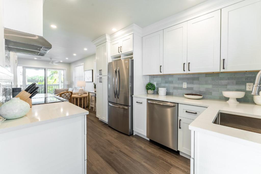 a kitchen with white cabinets and stainless steel appliances at Paradise Point by AvantStay Golf Course Living in Stock Island