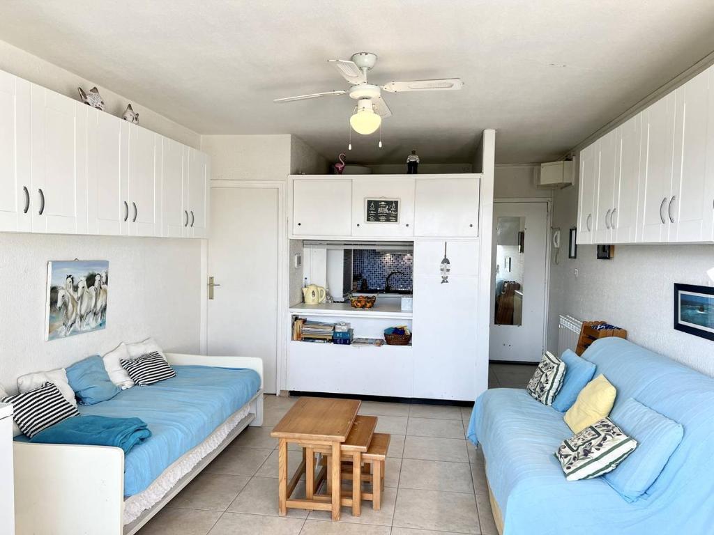 un salon avec deux canapés bleus et une cuisine dans l'établissement STUDIO CLIMATISE 3 PERSONNES A PROXIMITE IMMEDIATE MER ET PLAGE, au Grau-du-Roi