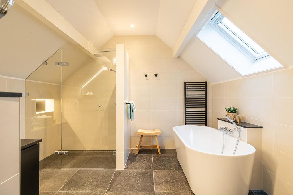 een badkamer met een groot bad en een douche bij Villa Zuiderduin in Zoutelande