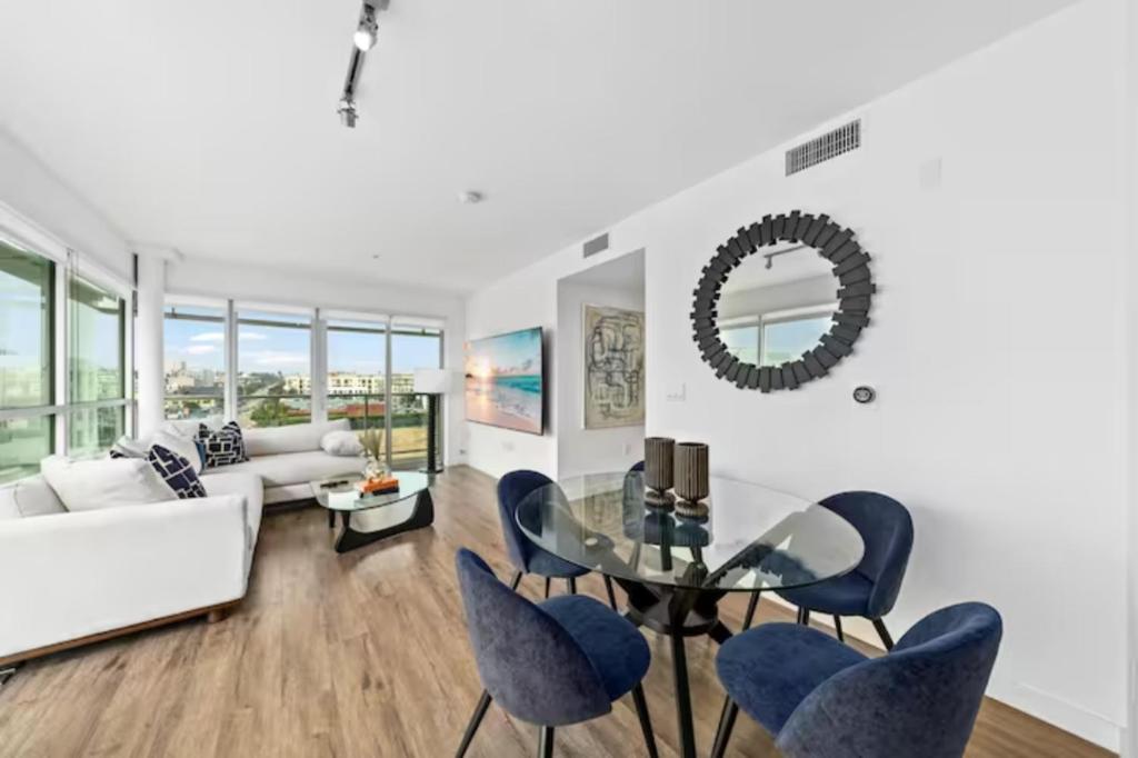 een woonkamer met een glazen tafel en blauwe stoelen bij Luxurious SM Penthouse with Panoramic Ocean Views in Los Angeles