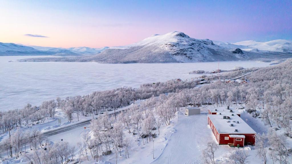 un bâtiment rouge dans la neige à côté d'une montagne dans l'établissement Hostel Saana, à Kilpisjärvi