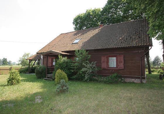 a small house in a field with a yard at Apartamenty Pod Lipami in Junoszyno