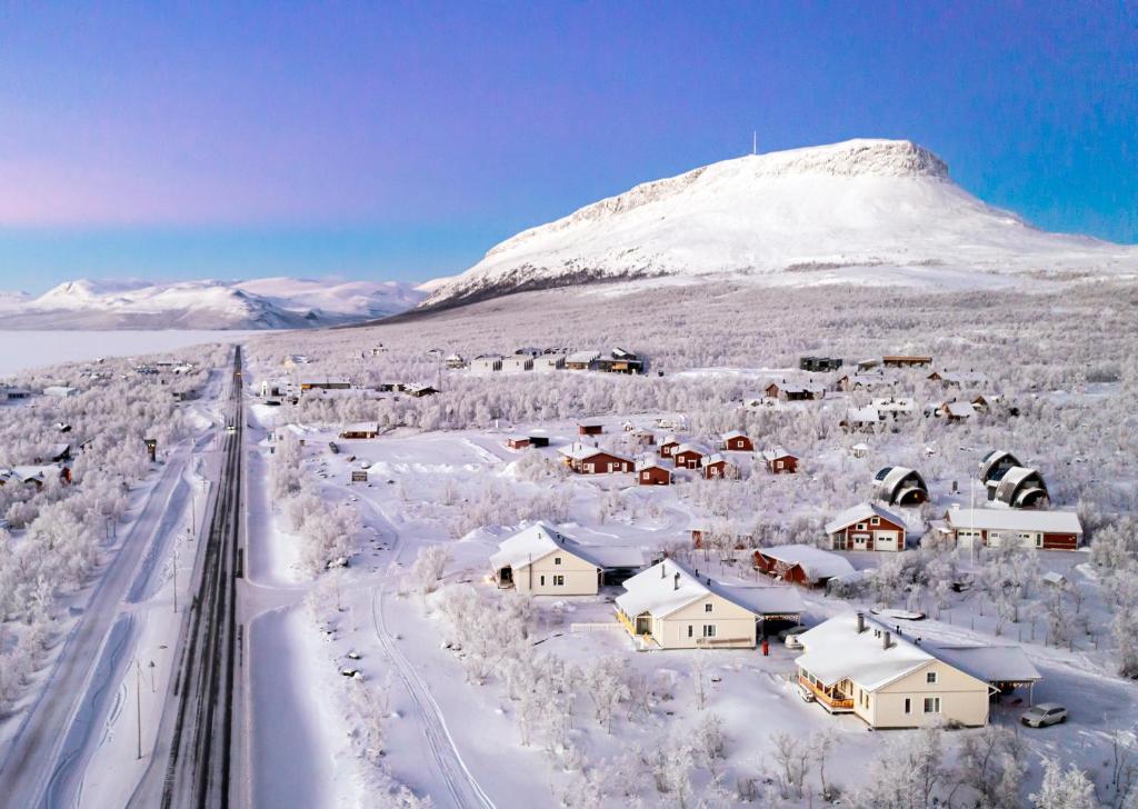 ein schneebedecktes Dorf mit einem Berg im Hintergrund in der Unterkunft Aurora Apartment Kilpisjärvi in Kilpisjärvi