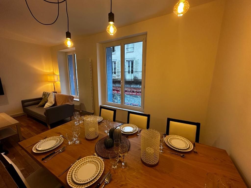 une salle à manger avec une table en bois, des assiettes et des verres dans l'établissement Belle maison de ville au cœur du village de montagne, à Vic-sur-Cère