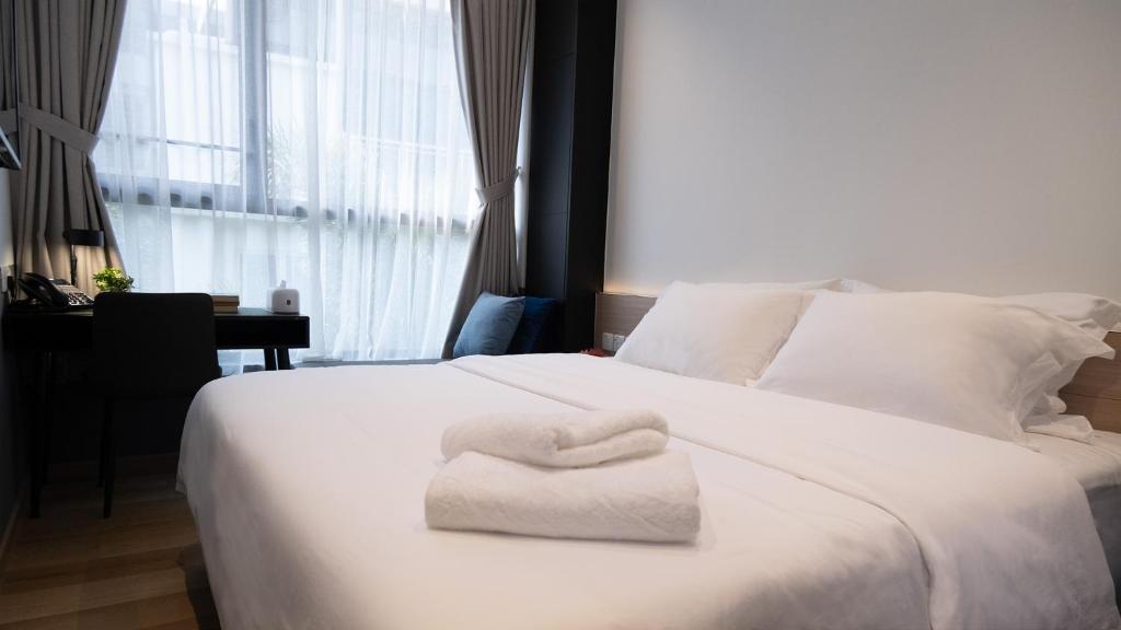 Un dormitorio con una cama blanca con una toalla. en VicHaus Serviced Apartment en Singapur
